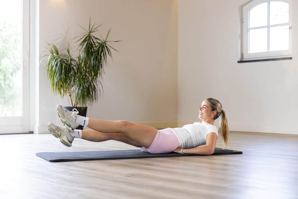 Vrouw die buik oefening thuis doet op fitnessmat